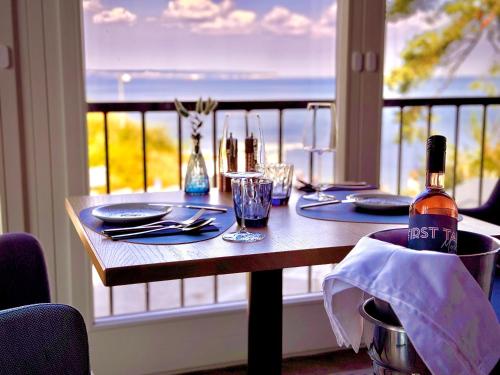 a table with a bottle of wine and a view of the ocean at FIRST im FIRST Sellin, Penthouse Meerselig mit Ostseeblick und Dachterrasse in Ostseebad Sellin