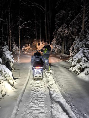 a man standing next to a snowmobile in the snow at Holmens Boende och Event in Luleå