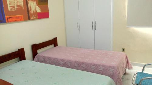 a bedroom with two beds and a cabinet at Quarto aconchegante Jatiúca in Maceió