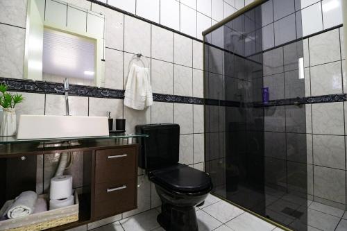 a bathroom with a black toilet and a sink at Nete Getaway! in Palhoça