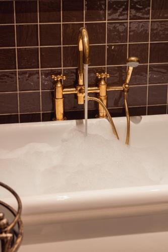 a bath tub with a water faucet at No.124 by GuestHouse, Brighton in Brighton & Hove