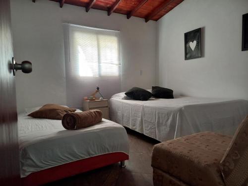 a bedroom with two beds and a chair and a window at EpicBK Casa Campestre en San Pedro Antioquia in Zatra Tobón