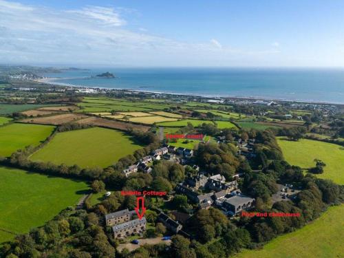an aerial view of a house in a field next to the ocean at Saddle Cottage in Penzance