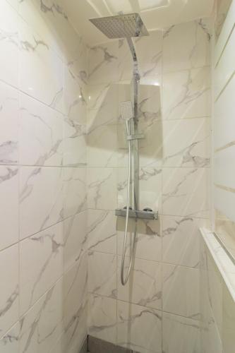 La salle de bains est pourvue d'une douche et de murs en marbre blanc. dans l'établissement Appartement moderne et élégant Michel Torrent 2, à Perpignan