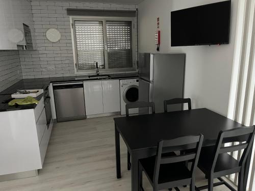 a kitchen with a table and a black table and chairs at Alojamento Mondinense in Mondim de Basto