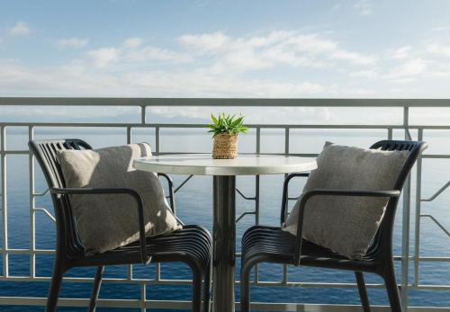 a table and two chairs on a balcony with the ocean at Infinity Hotel Gytheio in Gythio