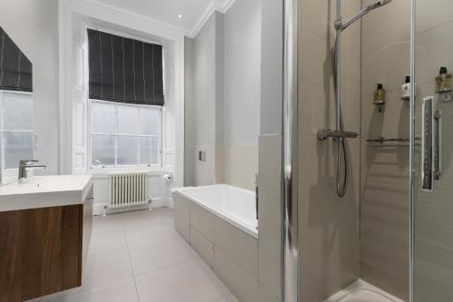 a bathroom with a shower and a tub and a sink at Destiny Scotland - Hill Street Apartments in Edinburgh