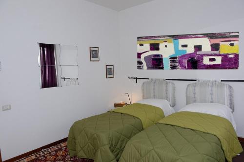 ローマにあるTintoretto Inn B&Bの緑の枕2つと壁に絵画が備わるベッドルーム1室