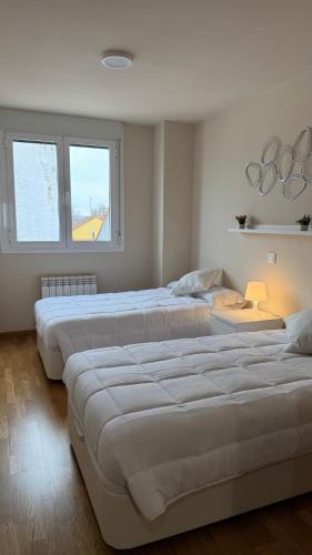 three beds in a room with two windows at Apartamentos Suites Iscar in Iscar