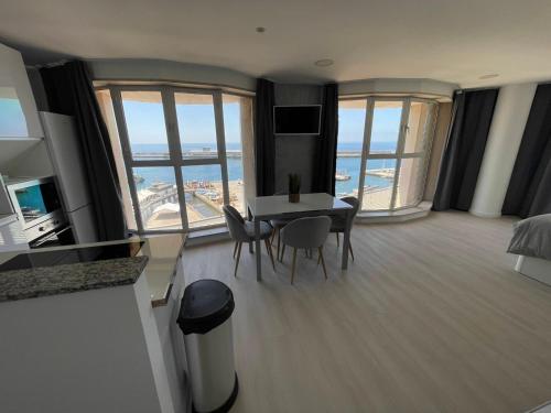 a living room with a table and chairs and windows at Center Marina view Silver Studio in Funchal