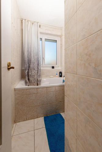 La salle de bains est pourvue d'une baignoire, d'une douche et d'une fenêtre. dans l'établissement Appart F3 Cosy proche Paris-Orly-Saclay, à Massy