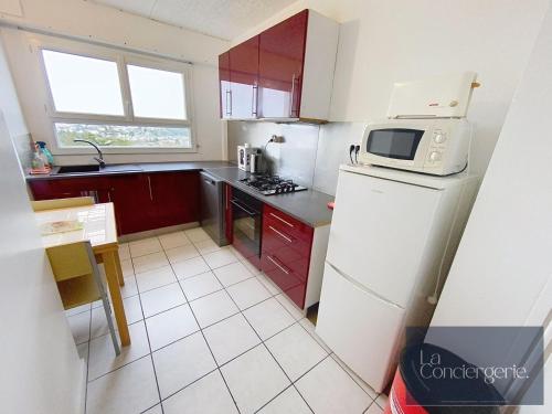 La cuisine est équipée d'un réfrigérateur blanc et d'un four micro-ondes. dans l'établissement Appart avec vue-Les Rocs-Poitiers-LaConciergerie, à Poitiers