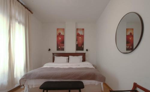a bedroom with a bed with a mirror and a chair at 1951 Suites in Kalabaka