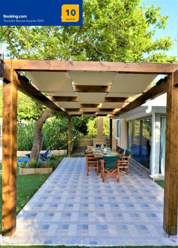 a patio with a table and chairs under a wooden pergola at Private Beach House Irene Mare in Poros
