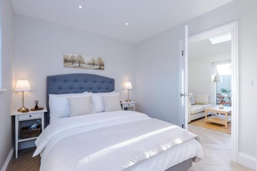 a white bedroom with a large bed with a blue headboard at Leaholme Lodge in Chester