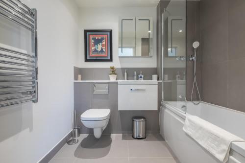 a white bathroom with a toilet and a bath tub at Fabulous Central Apt With Balcony & Parking in Cambridge