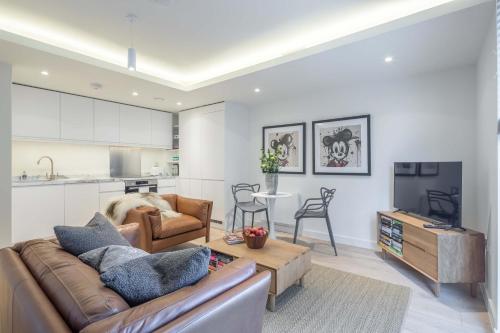 a living room with a couch and a tv and a kitchen at Stunning Central Apt With Parking in Cambridge