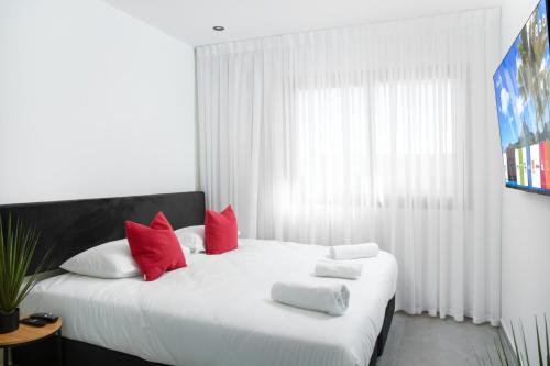 a bedroom with a large white bed with red pillows at אשראם אילת in Eilat