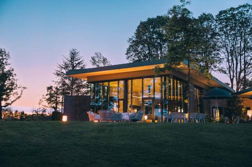 Le Bois d’Alice في Chanoz-Châtenay: منزل به الكثير من النوافذ والكراسي