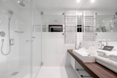 a white bathroom with a shower and a sink at Marine Hotel by Zdrojowa in Kołobrzeg