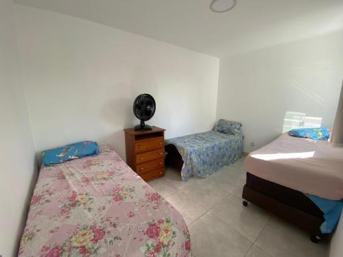 a bedroom with two beds and a dresser and a chair at Casa de praia Jacuipe Condomínio Planeta Água 1 in Campos