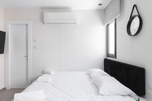 a white bedroom with a bed and a mirror at אשראם אילת in Eilat