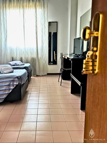 a room with two beds and a desk and a television at Verdemilia Hotel in Anzola dell'Emilia