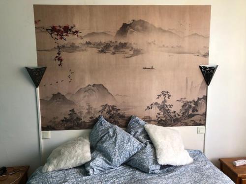 a bedroom with a painting above a bed with pillows at Chambre - Maison La Libéllule in Besançon