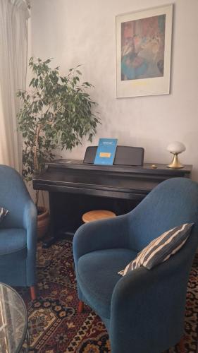 a living room with a piano and two chairs and a laptop at Chambre avec sdb privative - Maison La Libéllule in Besançon