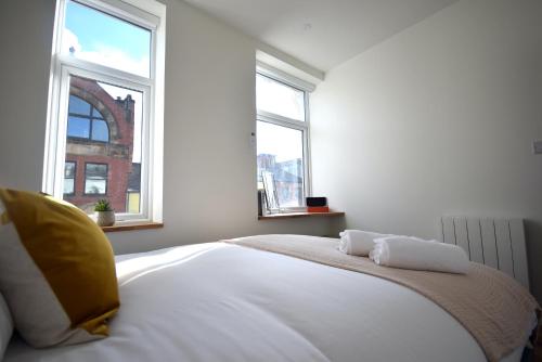 a bedroom with a bed with two windows at CITYeSCAPE - 2BR apt 2 ensuite Sofa Bed NQ in Manchester