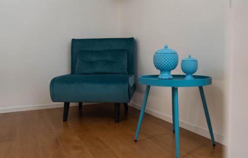 a blue chair and a table with a vase on it at Lues Rooms in Ragusa