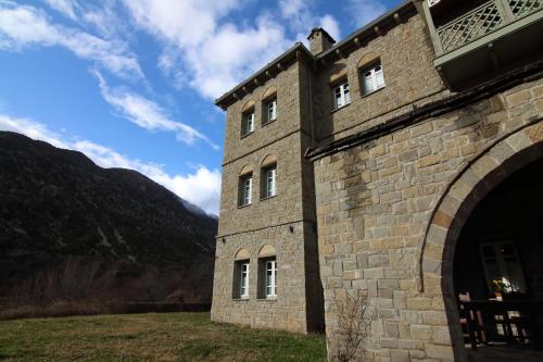 a large brick building with a mountain in the background at Hotel Petrotechno in Tsepelovo