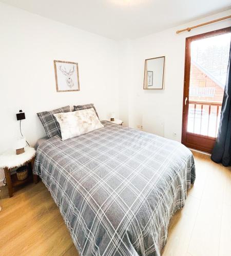 a white bedroom with a bed and a window at Chalet Joue du loup 6-7 pers in Le Dévoluy