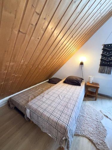 a bed in a room with a wooden ceiling at Chalet Joue du loup 6-7 pers in Le Dévoluy