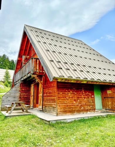 a red barn with a metal roof at Chalet Joue du loup 6-7 pers in Le Dévoluy