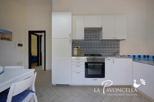 a kitchen with white cabinets and a stove top oven at Case Vacanze La Pavoncella in Teulada