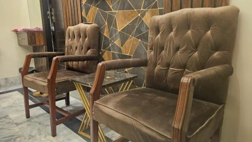 two chairs and a table in a room at Hotel Moon Light in Karachi