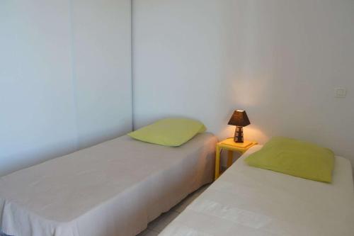 deux lits dans une chambre avec une lampe sur une table dans l'établissement SP020-A06 Appt 3 pièces 6 couchages SAINT PIERRE LA MER, à Saint Pierre La Mer