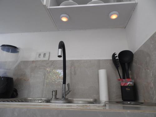 a kitchen counter with a sink and a kitchenilit at Apartamento Inteligente - Japaratinga in Japaratinga