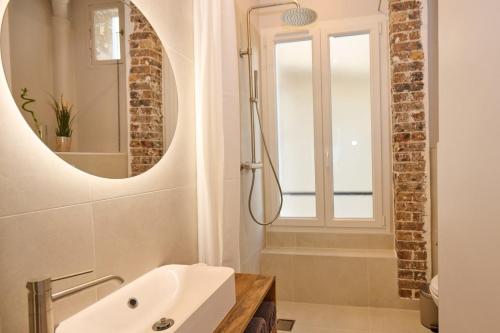 une salle de bain avec un lavabo et un miroir dans l'établissement Geranimus Picasso Heart of Paris, à Paris
