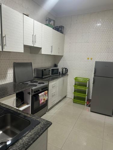 eine Küche mit weißen Schränken und einem Herd mit Backofen in der Unterkunft Appartement moderne 3 chambres au centre-ville de Kinshasa in Kinshasa