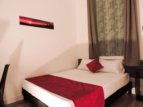 a small bedroom with a bed with a red blanket at Hotel San Marcos in Manizales
