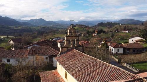 a village with a church and houses and mountains at El Balcon del Horreo in Piloña