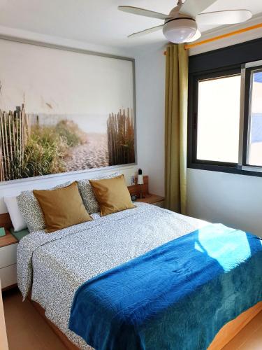 a bedroom with a bed with a blue comforter and a window at Enjoy the beach in Bellreguart