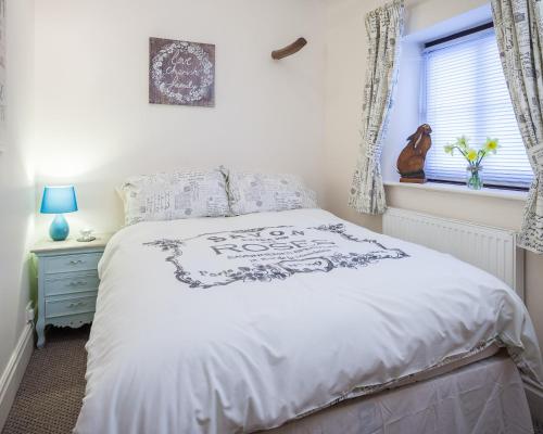a bedroom with a bed with a white bedspread and a window at Skipbridge Farm Cottages in Green Hammerton