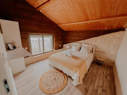 a bedroom with a bed and a wooden ceiling at La Maison Des Pierres Blondes in Orban