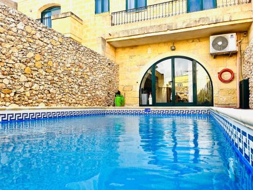 a swimming pool in front of a building at 4 Bedroom Farmhouse with Private Pool in Xaghra Gozo in Xagħra