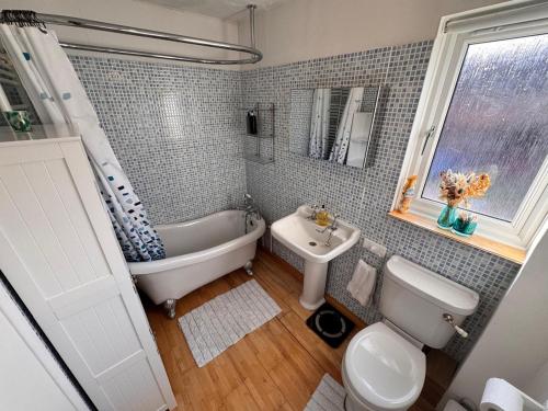 a bathroom with a tub and a toilet and a sink at Windsor & Legoland Stay, Slough & Free Parking - Berkshire in Burnham