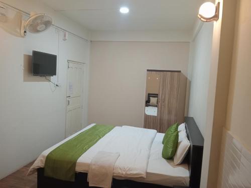 a small bedroom with a bed and a tv at Rolyda Guest House in Shillong
