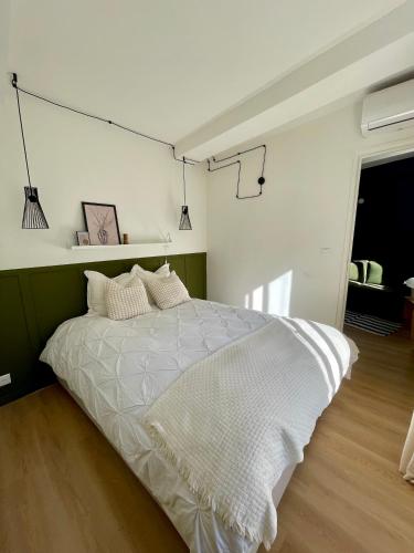 une chambre avec un lit blanc et un mur vert dans l'établissement Cosy 1 Bedroom Place Massena, à Nice